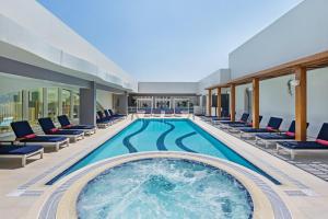 a swimming pool in a hotel with lounge chairs at Al Maha Arjaan by Rotana in Abu Dhabi