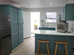 a kitchen with green cabinets and a counter with stools at Mia Nina in Heatherlands