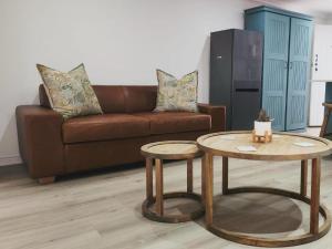 a living room with a brown couch and two tables at Mia Nina in Heatherlands
