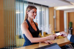 a woman is handing a person a piece of paper at Hala Arjaan by Rotana, Deluxe Hotel Apartments in Abu Dhabi +48 photos