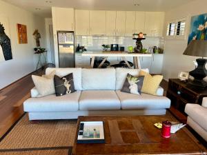 a living room with a couch and a kitchen at Perfect weekend getaway plus golf at your doorstep in Salamander Bay