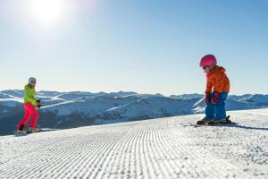 a couple of people skiing down a snow covered slope at Hotel Lärchenhof in Katschberghöhe