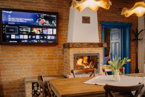 a dining room with a fireplace and a television on a brick wall at Heritage Guesthouse in Bartoştana