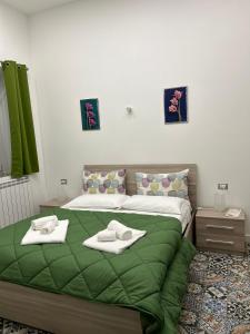 a bedroom with a green bed with towels on it at B&B Flora in Piazza Armerina
