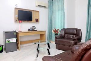 a living room with a couch and a chair and a television at Aotel Hotel Lagos Owodunni in Ikeja