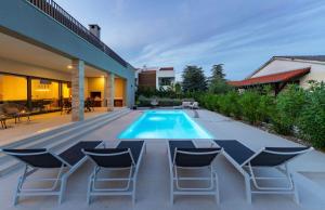 a swimming pool with chairs and a house at Villa Karpa in Pridraga