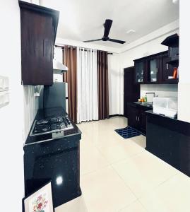a kitchen with black cabinets and a stove top oven at Rugee R Villa in Negombo