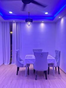 a dining room with purple lighting and a table and chairs at HomestayBondaFaiiha in Port Dickson
