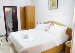 a bedroom with a white bed with a towel on it at Aotel Hotel Lagos Owodunni in Ikeja