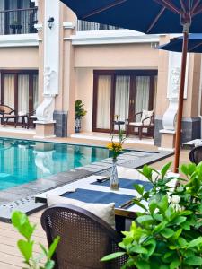 a pool with chairs and a table with an umbrella at CHINO@NIMMAN Luxury Boutique Hotel in Chiang Mai