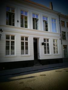 een wit huis met een deur en ramen bij b&b les invités in Brugge
