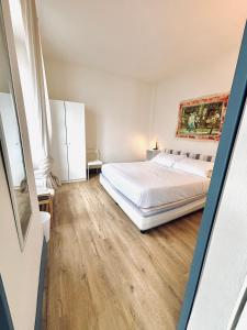 a bedroom with a white bed and a wooden floor at -Ortaflats- Appartamento Gli Archi in Orta San Giulio