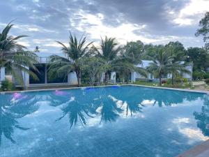 a large swimming pool with palm trees and a building at F&F Poolvilla Beach Tha Chana in Suratthani +106 photos