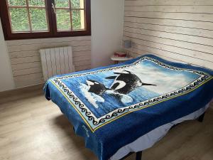 a bed with a blue blanket with two birds on it at Chambre in Saint-Pierre-dʼAurillac