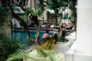 a woman sitting next to a pool at a hotel at Fourteen Roses Beach Hotel in Legian