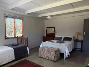 a bedroom with two beds and a table and window at Shabach Farm in Hartebeest Rivier