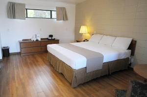 Un dormitorio con una gran cama blanca y una mesa en CCBC Resort Hotel - A Gay Men's Resort, en Cathedral City