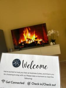 a sign with a welcome sign in front of a fireplace at Koshoka Suites in Ongwediva