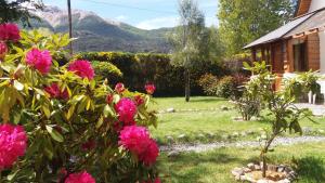 un jardín con flores rosas frente a una casa en Cabañas Maite en Villa La Angostura