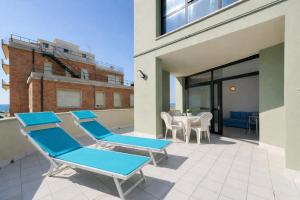a patio with blue lounge chairs and a table at AMA Marena Apartments in Pesaro +4 photos