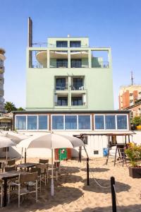 a building with tables and umbrellas in front of it at AMA Marena Apartments in Pesaro