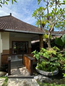a small house with a wooden walkway in a garden at Dava Guest House Gianyar in Gianyar +12 photos