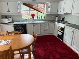 a kitchen with white cabinets and a table with a red rug at Riverchapel Guesthouse in Courtown