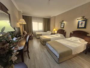 a hotel room with two beds and a desk at Büyük Sümela Otel in Macka