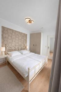 a white bedroom with a large white bed with white sheets at FeWo Jette in Warnemünde