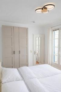 a white bedroom with a white bed and a ceiling fan at FeWo Jette in Warnemünde