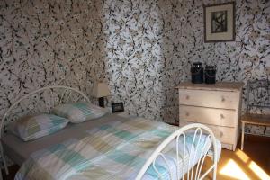 ein Schlafzimmer mit einem Bett, einer Kommode und Tapeten in der Unterkunft Vakantiewoning Cosy Corner in Ypern