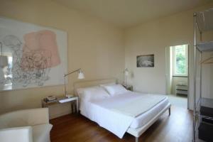 a white bedroom with a bed and a chair at Villa Rosmarino in Camogli