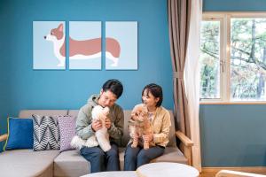 two women sitting on a couch holding cats at Seagaia Forest Cottages in Miyazaki