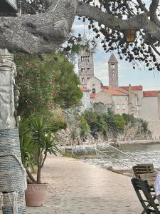 a building with a clock tower on the shore of the water at Apartman Blaženka in Kampor