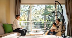 a group of people sitting in a room with a swing at Seagaia Forest Cottages in Miyazaki