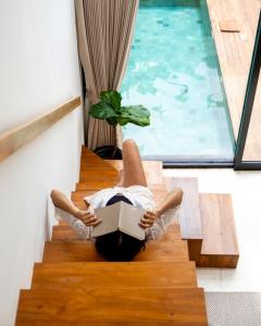 a woman laying on the stairs reading a book at Tannari Villa Ubud in Ubud