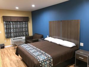 Deluxe Inn & Suites - Baytown في باي تاون: غرفة نوم بسرير كبير وكرسي