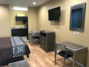 um pequeno quarto com uma cama, uma mesa e cadeiras em Deluxe Inn & Suites - Baytown em Baytown