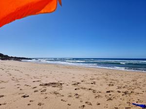 a beach with an orange umbrella and the ocean at Geckos Rest Southbroom in Southbroom