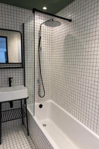 a white tiled bathroom with a tub and a sink at Hôtel Le Versailles in Villefranche-sur-Mer +41 photos