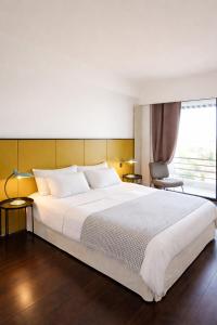 a bedroom with a large white bed and a window at Hôtel Le Versailles in Villefranche-sur-Mer