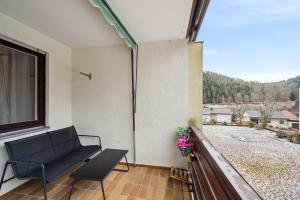 a balcony with a black bench and a window at Ramoni Apartments - Abendgold in Enzklösterle