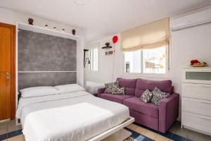 a bedroom with a bed and a purple couch at Ático la Azotea con terraza PRIVADA in Seville