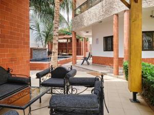 a patio with chairs and a table and a palm tree at Tekrour- la case des hôtes- Suite privée-chambre, salon et cuisine complete in Mbour