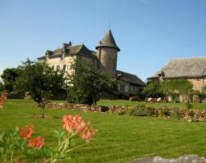 a large house with a tower on a green lawn at Chambres d'Hôtes du Hameau Les Brunes in Bozouls