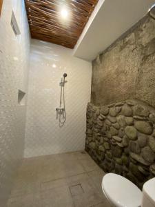 a bathroom with a toilet and a stone wall at Dava Guest House Gianyar in Gianyar