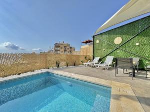 a swimming pool with chairs next to a building at Butterwave | 1BR Jacuzzi & Terrace in Kfar Aabida in Fad‘ūs