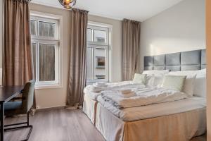 ein Schlafzimmer mit Bett, Schreibtisch und Fenstern in der Unterkunft Strandgata Hotel in Haugesund