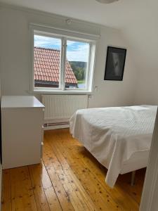 a white bedroom with a bed and a window at Dalagård i Insjön in Insjön