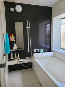 a bathroom with a tub and a sink and a mirror at Daizaifu Guest House 1 in Dazaifu
